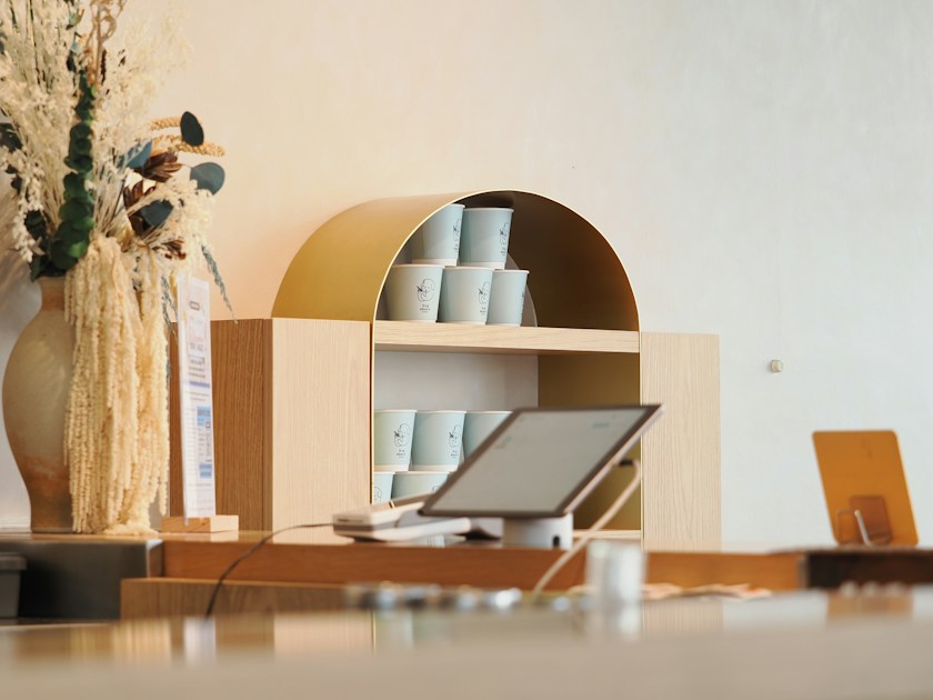 A cafe counter with dried flowers, cups, and a tablet