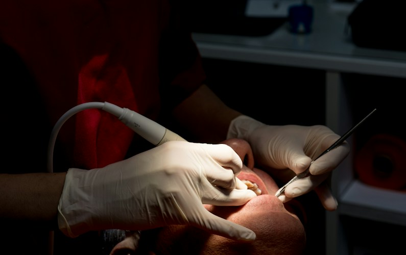 Dentist cleaning patient's teeth with tools
