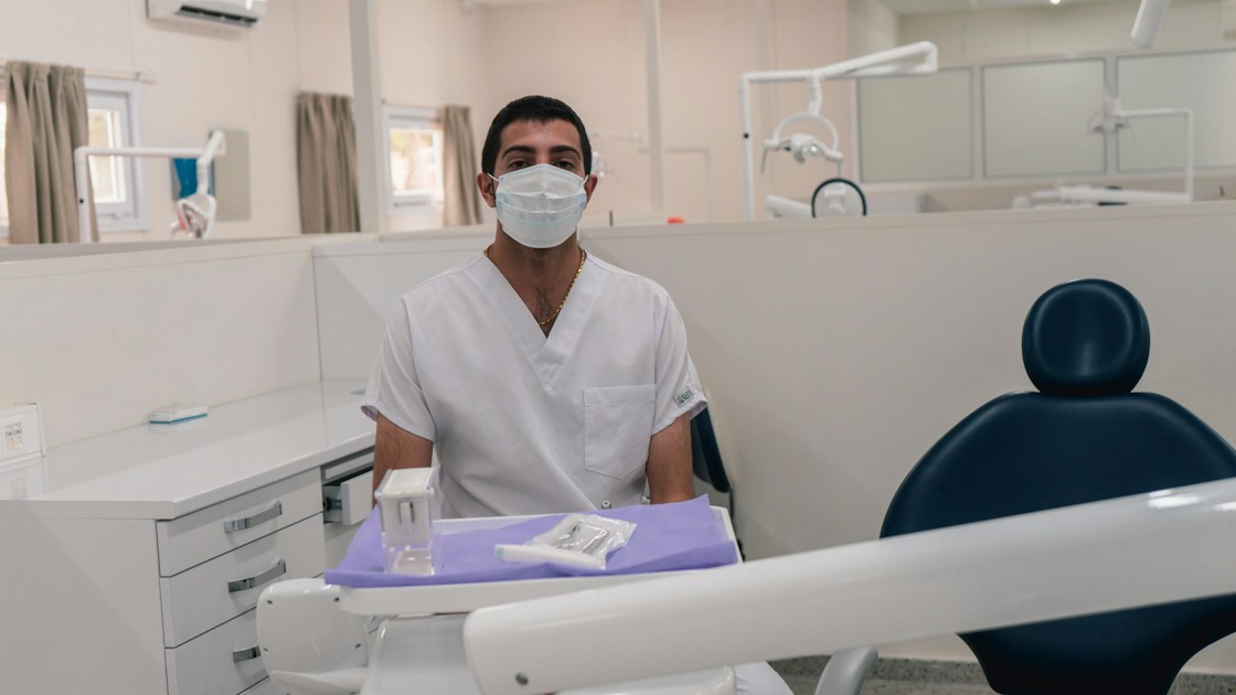 a man wearing a face mask sitting in a chair