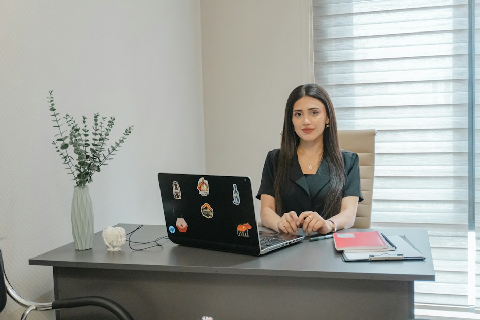 A woman sits at a desk with a laptop