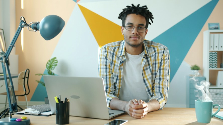 Man sitting at desk with laptop and steaming mug