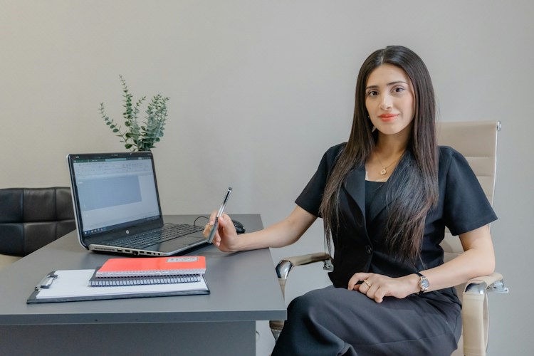 A woman sits at a desk with a laptop